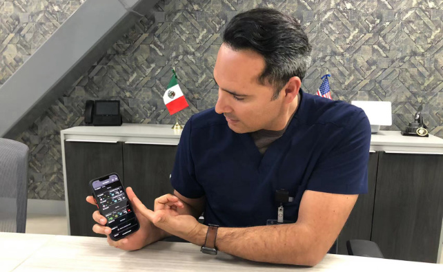 Héctor Acosta watching patient status on his phone